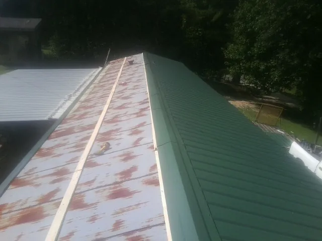 Old rusted panels beside newly installed green metal roofing — Wind Damage Roof Repair by Roofing Brothers in Marcus Hook