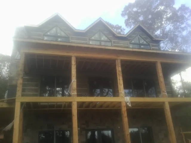 Dormers and porch framing on a large log home under construction — Roof Coating work by our crew in Marcus Hook