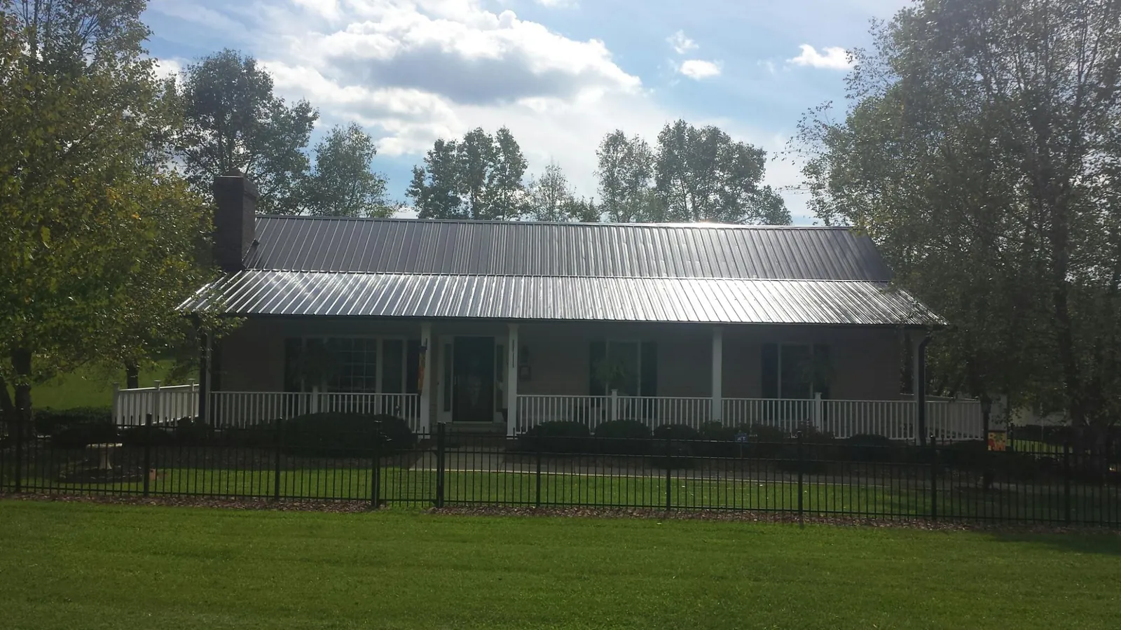 Gray metal roof on a brick ranch with a full width front porch — Gutter Guard Installation work by our crew in Marcus Hook