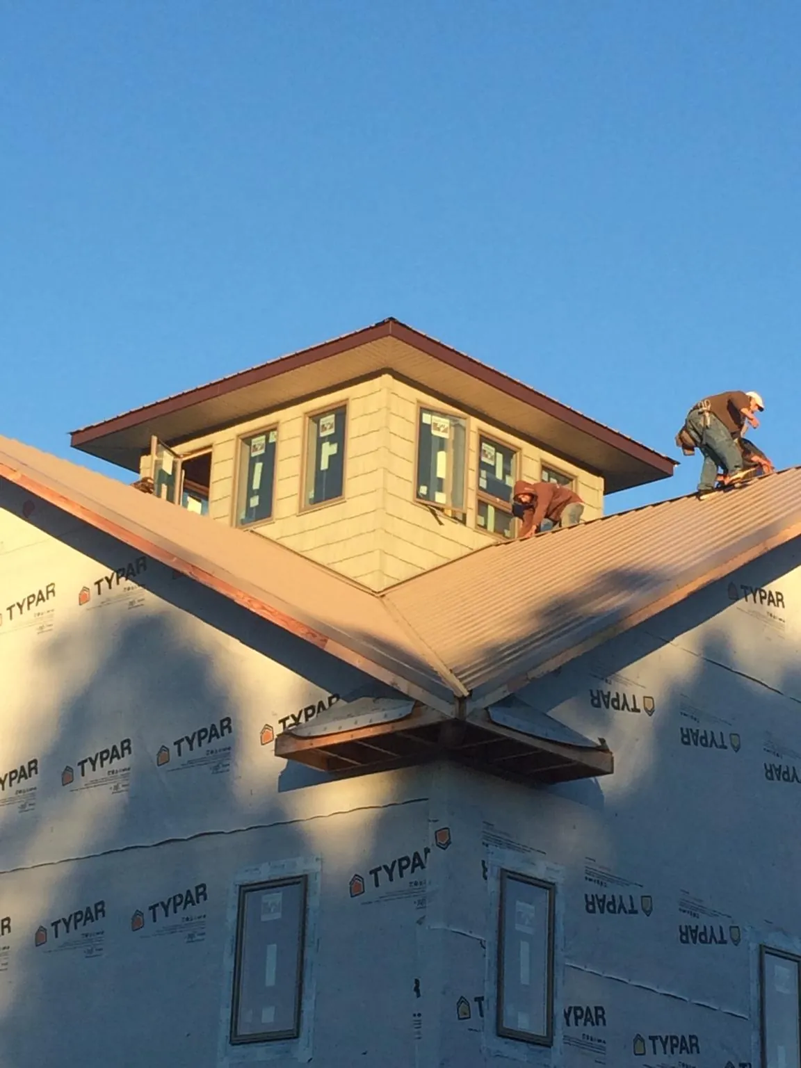 Roofers working around a rooftop cupola on a new metal roof at sunset — Roof Waterproofing in Marcus Hook by Roofing Brothers